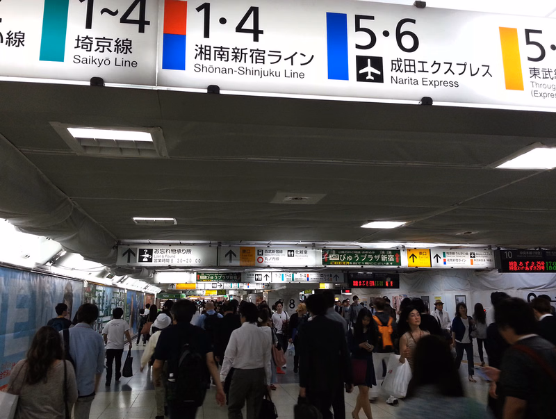 A large overhead sign in a train station displays route information, including "1～4埼京線 Saikyō Line" and "1・4湘南新宿ライン Shōnan-Shinjuku Line".