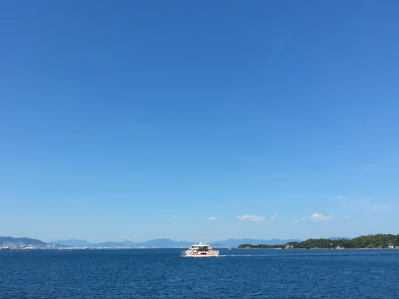 A serene seascape with a boat in the foreground and mountains in the distance.