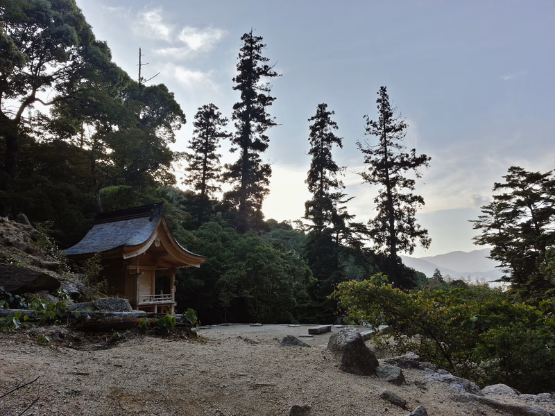 A serene Japanese landscape with a traditional wooden building nestled among tall trees.