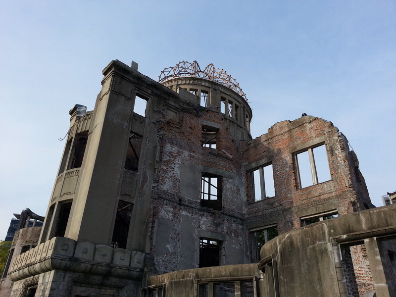 An image of a decaying, partially ruined brick building with exposed structural elements against a bright sky.