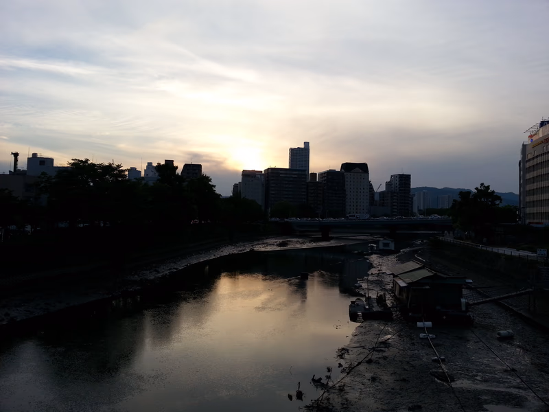 A serene river scene at sunset, with a city skyline in the background.