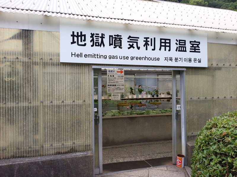 The sign in Japanese reads 'Beppu Gas Rooftop Gastronomy' and the English translation 'Hell emitting gas use greenhouse.'
