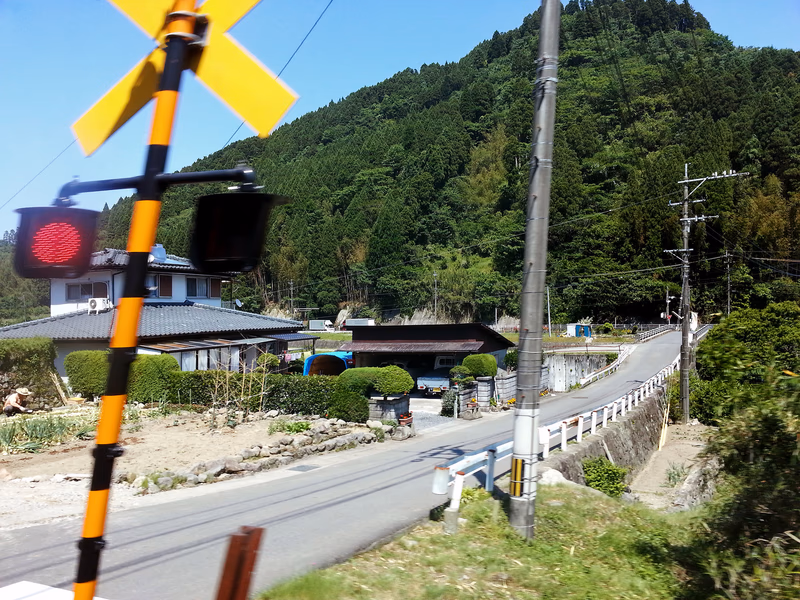 A photo of a road in a rural area with a traffic light and a building in the background, with a mountain in the distance.
