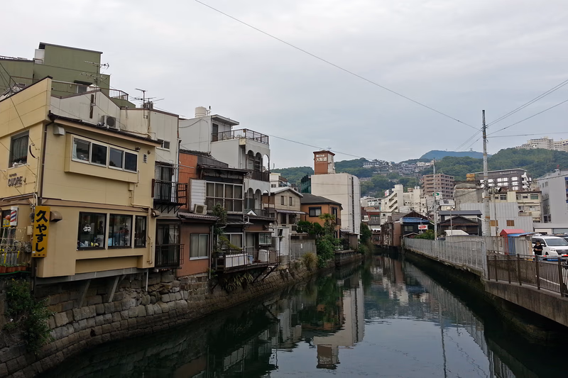 A serene urban scene with a waterway running through a neighborhood of traditional and modern buildings.