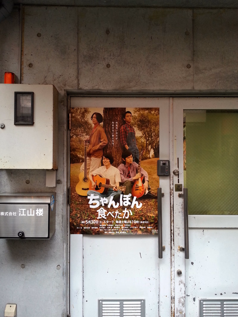 A photo of a restaurant entrance featuring a poster with the text "ちゃんぽん 食へたか" and a picture of several people.