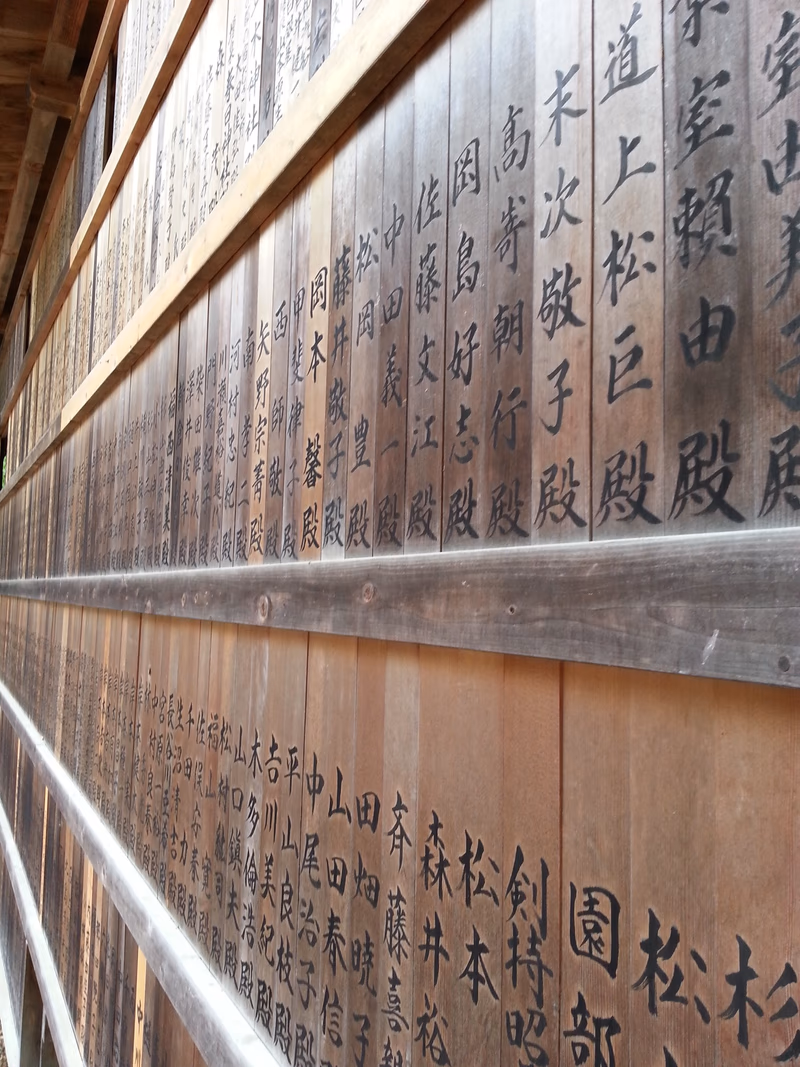A close-up photograph of wooden panels with Japanese calligraphy.