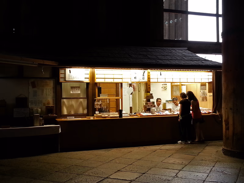 A food stand in a dimly lit area with people standing in front of it.