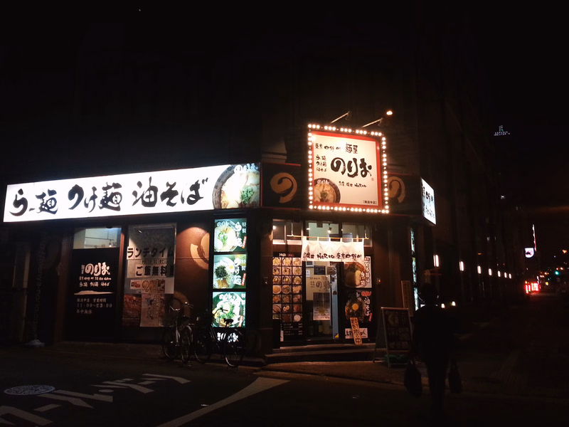 A Japanese restaurant at night with illuminated signs, one reading "らー麺 泡そば" and another displaying "のゆき".