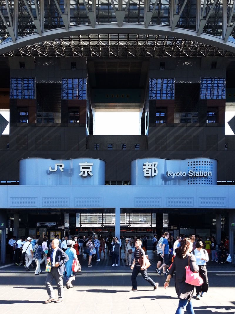 The exterior of Kyoto Station features large signage reading "JR 京都" and "Kyoto Station" above the entrance.