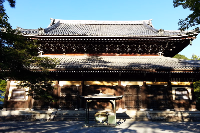 A photo of a traditional Japanese building with a tree and a table in front of it.