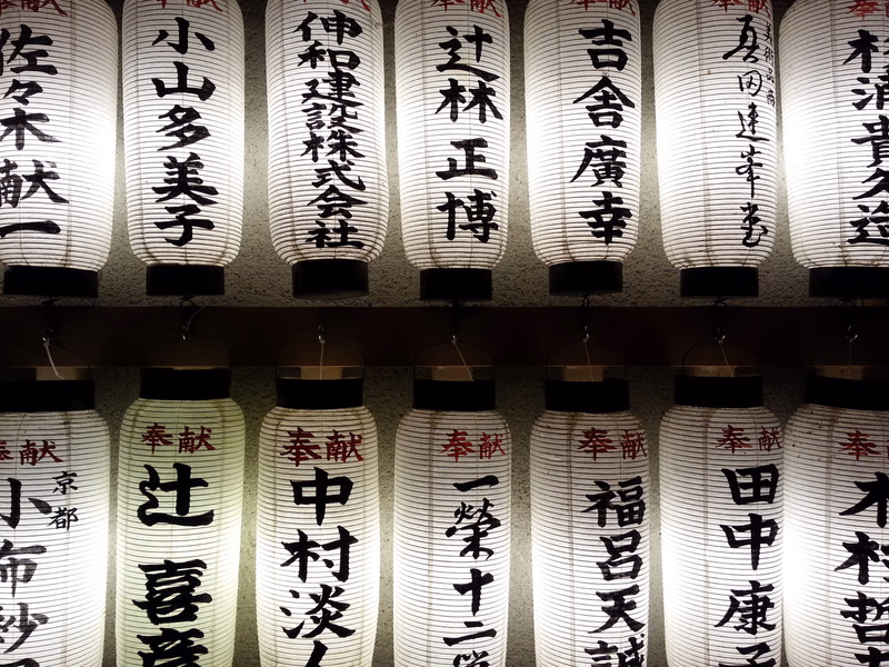 A collection of traditional Japanese lanterns with Japanese text displayed on them.