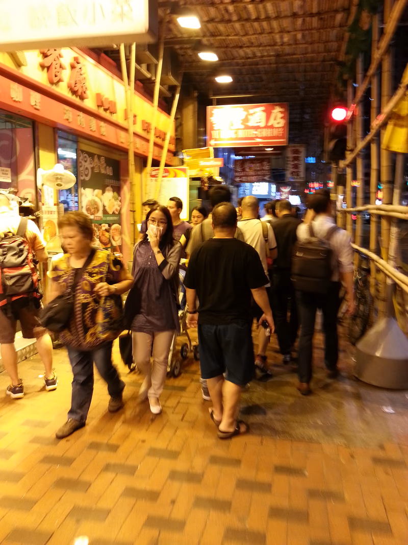 A bustling street scene in a city at night, with people walking and shopping, and colorful storefronts.