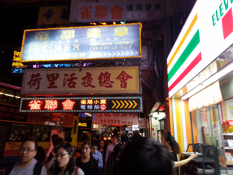A vibrant street scene in Kowloon City, Hong Kong, with colorful signs and a bustling crowd.