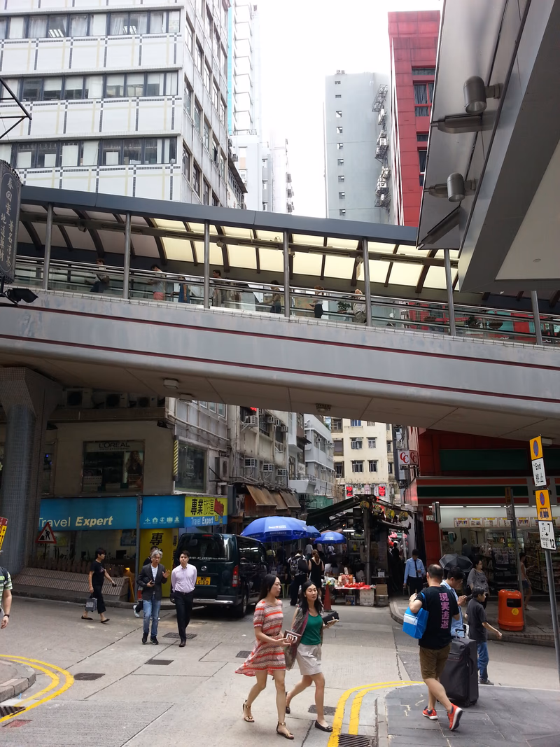 A photo of a skywalk in a city, with people walking on the street below and buildings surrounding the area.