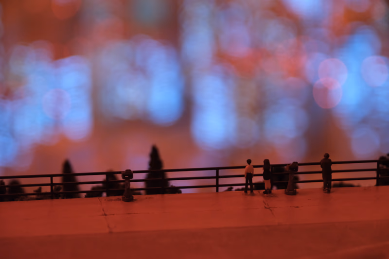 A miniature scene of a bridge with people and trees