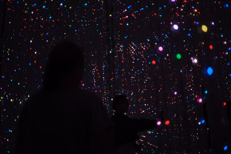 A photo of a person standing in front of a colorful, starry background.