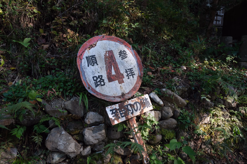 A circular white and red sign marked "順路 4 参拝" is set among mossy stones, next to a smaller sign reading "参道の跡".