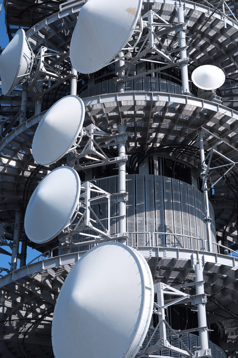 A large array of white satellite dishes and antennas are mounted on a complex, multi-tiered metal scientific structure.