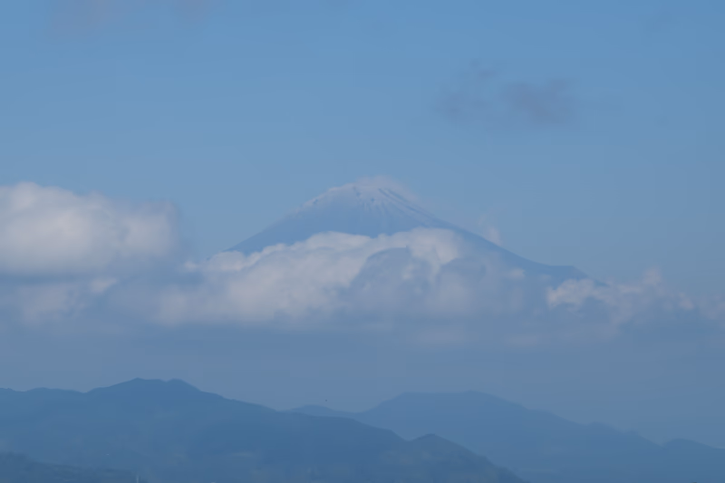A photograph of Mount Fuji, a famous mountain in Japan, surrounded by clouds and mountains.