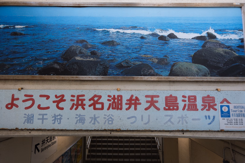 A sign welcomes visitors to 'ようこそ 浜名湖 湧井天島温泉' (Welcome to Hamana-ko Yuwai Tenjima Onsen) with text mentioning '湖干狩・海水浴・釣り・スポーツ'.