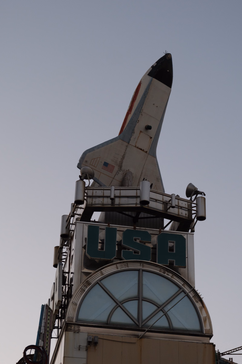 A large, white rocket sculpture stands atop a building featuring a sign that reads "USA".