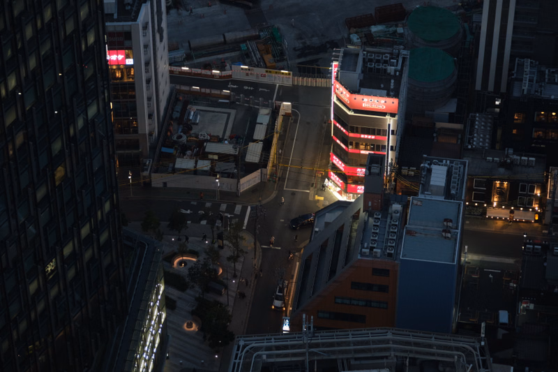 An aerial view of a dense urban area showing various buildings, some under construction, with a prominent red building displaying "BIG ECHO".