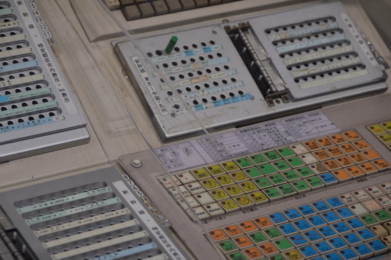 A complex vintage switchboard with numerous toggle switches and patch cords is shown, featuring labels like "新" and "10".
