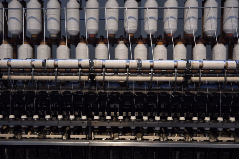 A photo of a textile machine with spools of thread.