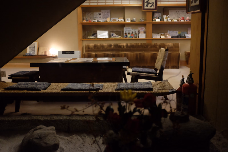 A traditional Japanese room featuring a low wooden table set with tatami mats and shelving displaying various items.