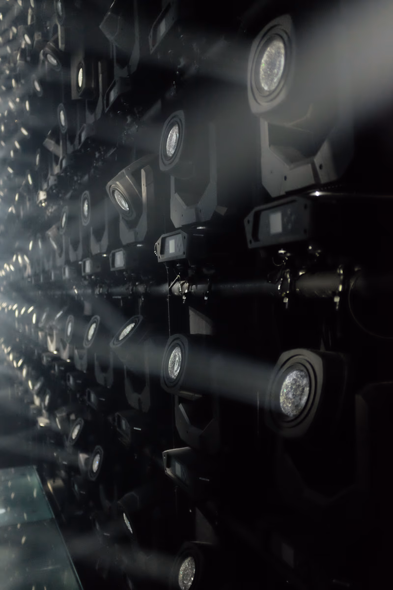 A photograph of a large array of spotlights illuminating a dark room.