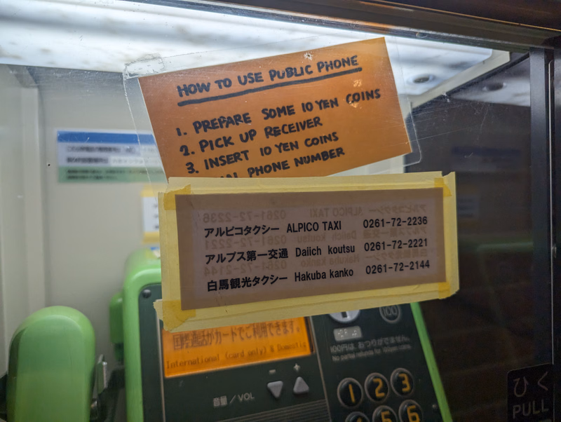 A sign titled "HOW TO USE PUBLIC PHONE" instructs users: "1. PREPARE SOME 10 YEN COINS 2. PICK UP RECEIVER 3. INSERT 10 YEN COINS 4. PHONE NUMBER"