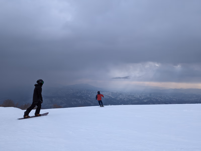 A snowy mountain landscape with two people enjoying winter sports.