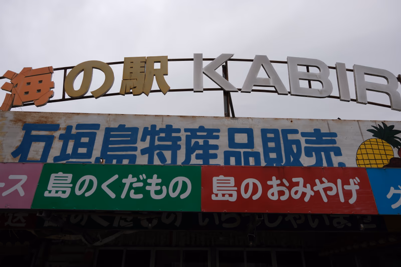 A signboard with a pineapple and the name of a place near Ishigaki, Okinawa, Japan. The signboard is in Japanese and English.