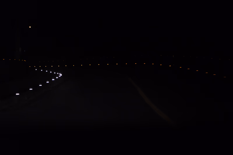 A photograph of a road at night with orange dots.
