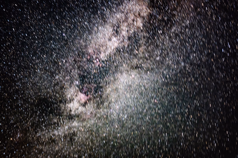 A wide-field photograph captures the dense band of the Milky Way galaxy stretching across a dark night sky filled with countless stars.