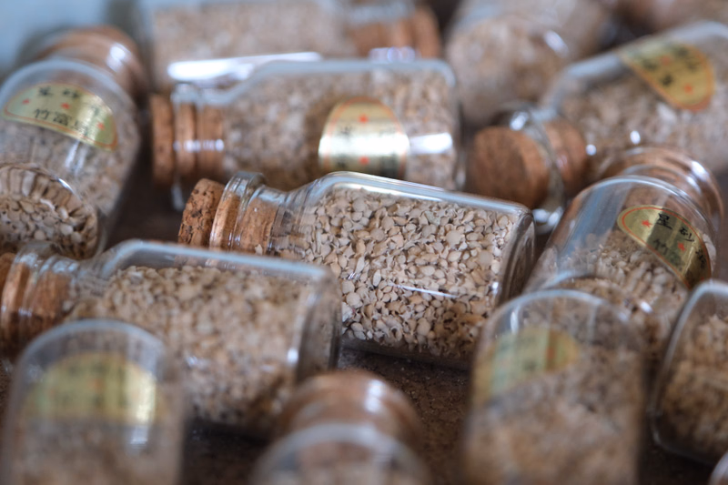 A collection of small glass jars filled with various ground spices and seasonings are displayed on a brown surface.
