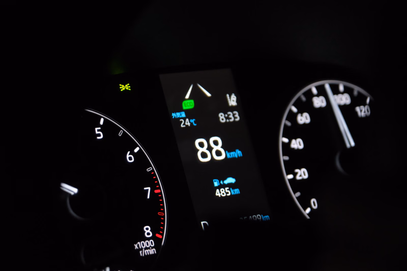 A close-up of a car dashboard showing a digital display with speed at 88 km/h, distance at 485 km, and time 8:33.