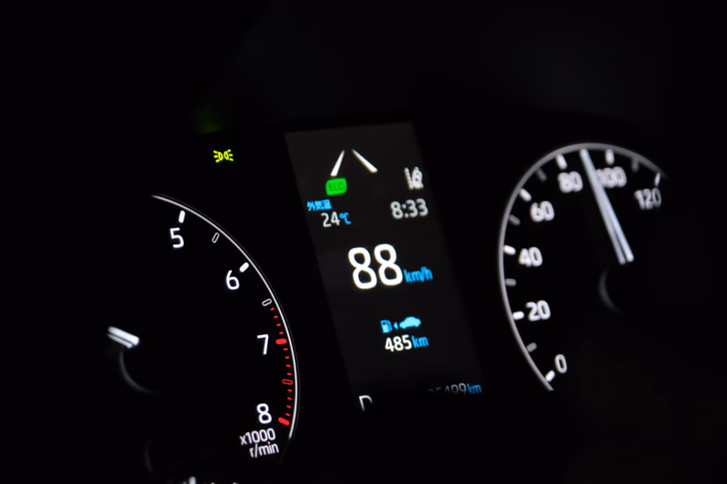 A close-up shot of a car dashboard with a speedometer, tire pressure gauge, and a digital display showing information such as temperature, time, and fuel efficiency.