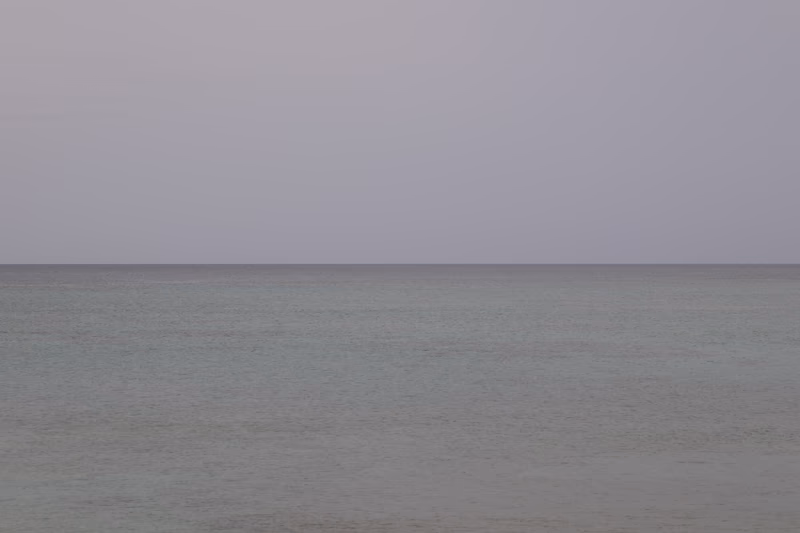 A photo of a vast, calm sea under a grey sky.