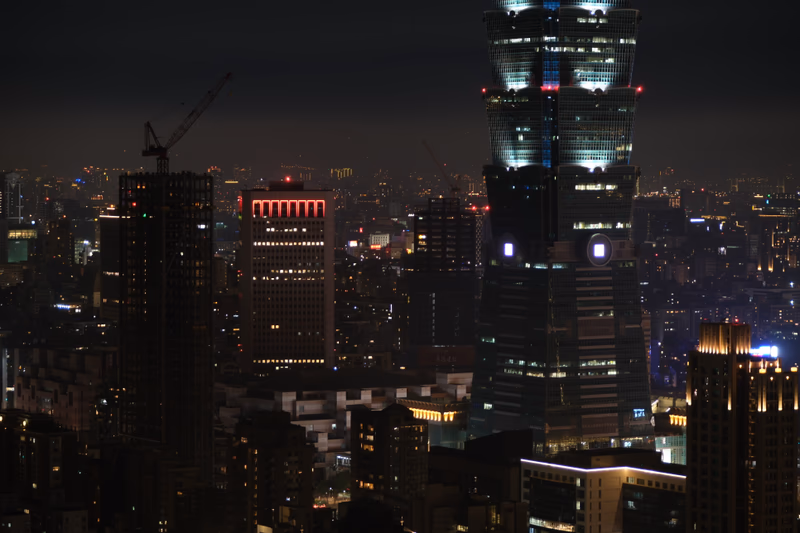 A night view of a city with tall buildings and a bright tower.