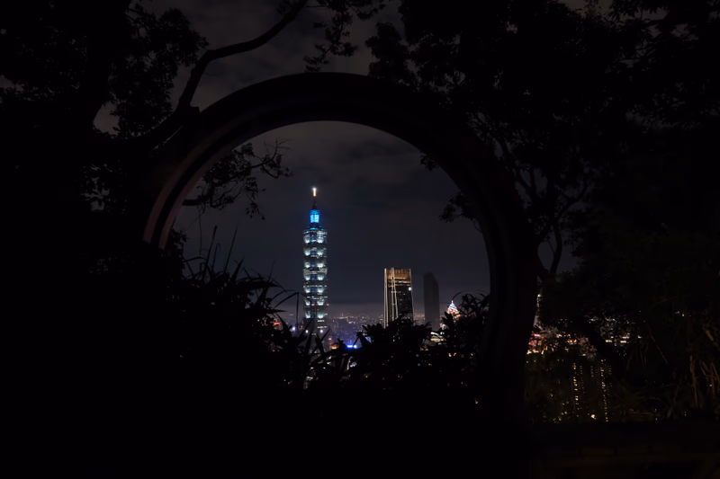 A night view of Taipei, Taiwan, with the iconic Taipei 101 skyscraper illuminated in blue lights.