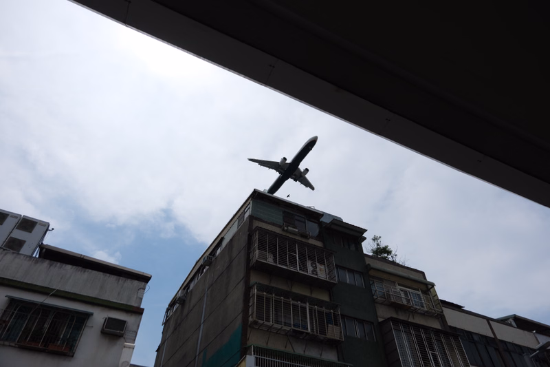 A large airplane sculpture is visible against a cloudy sky, positioned above a multi-story building.