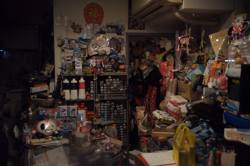 A cluttered indoor shop filled with various collectibles, toys, and merchandise displayed on shelves and tables.
