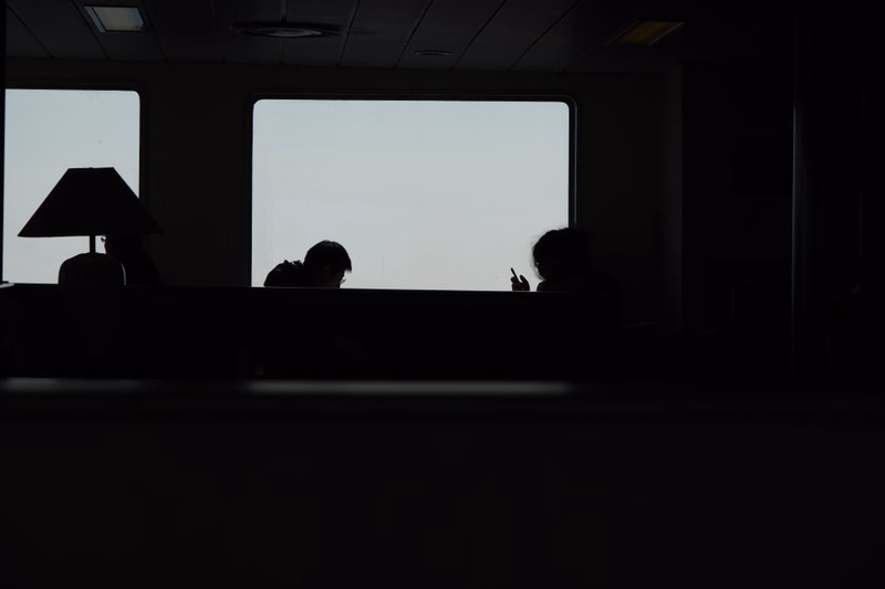 Silhouettes of several people are visible inside an office looking out through a large window.