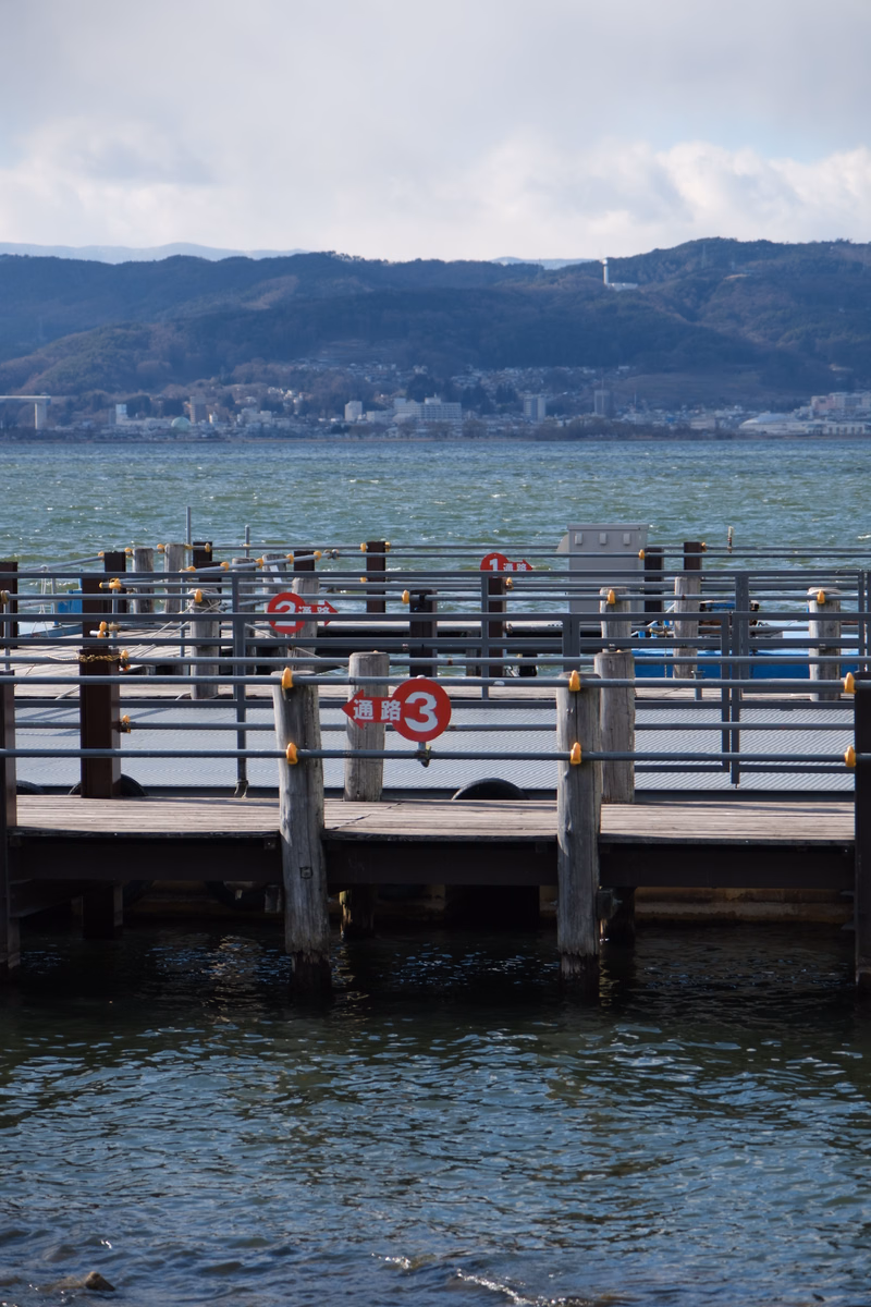 A wooden pier extends over the water with a red and white sign displaying "通路 3" visible on the railing.