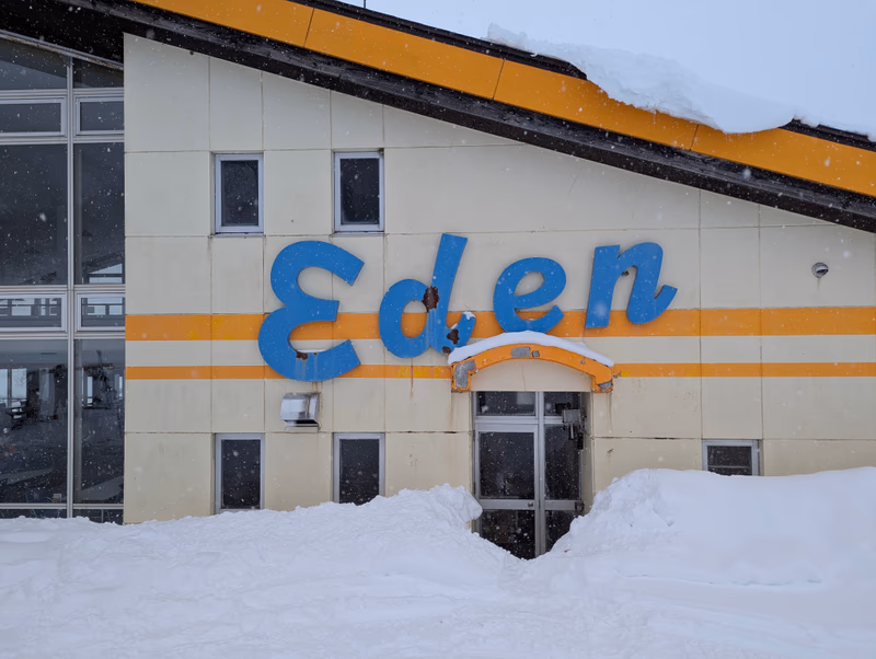 A snowy building with a sign that says 'Eden' and snow falling around it.