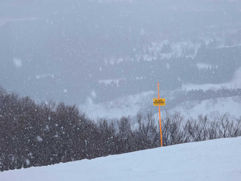 A snowy mountain landscape with a sign in the foreground.