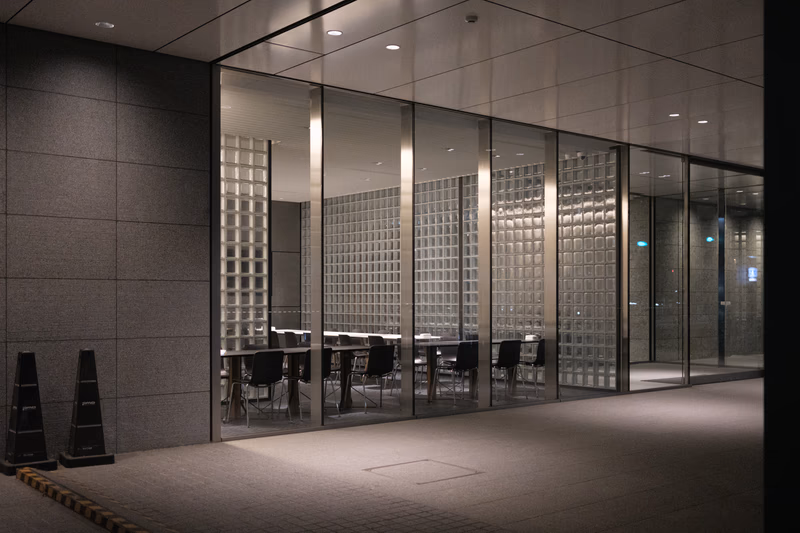 A modern office space with glass walls and a conference table.