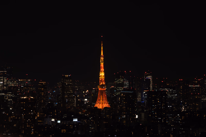 The Tokyo Skytree is illuminated at night, standing tall above the dense cityscape lights.