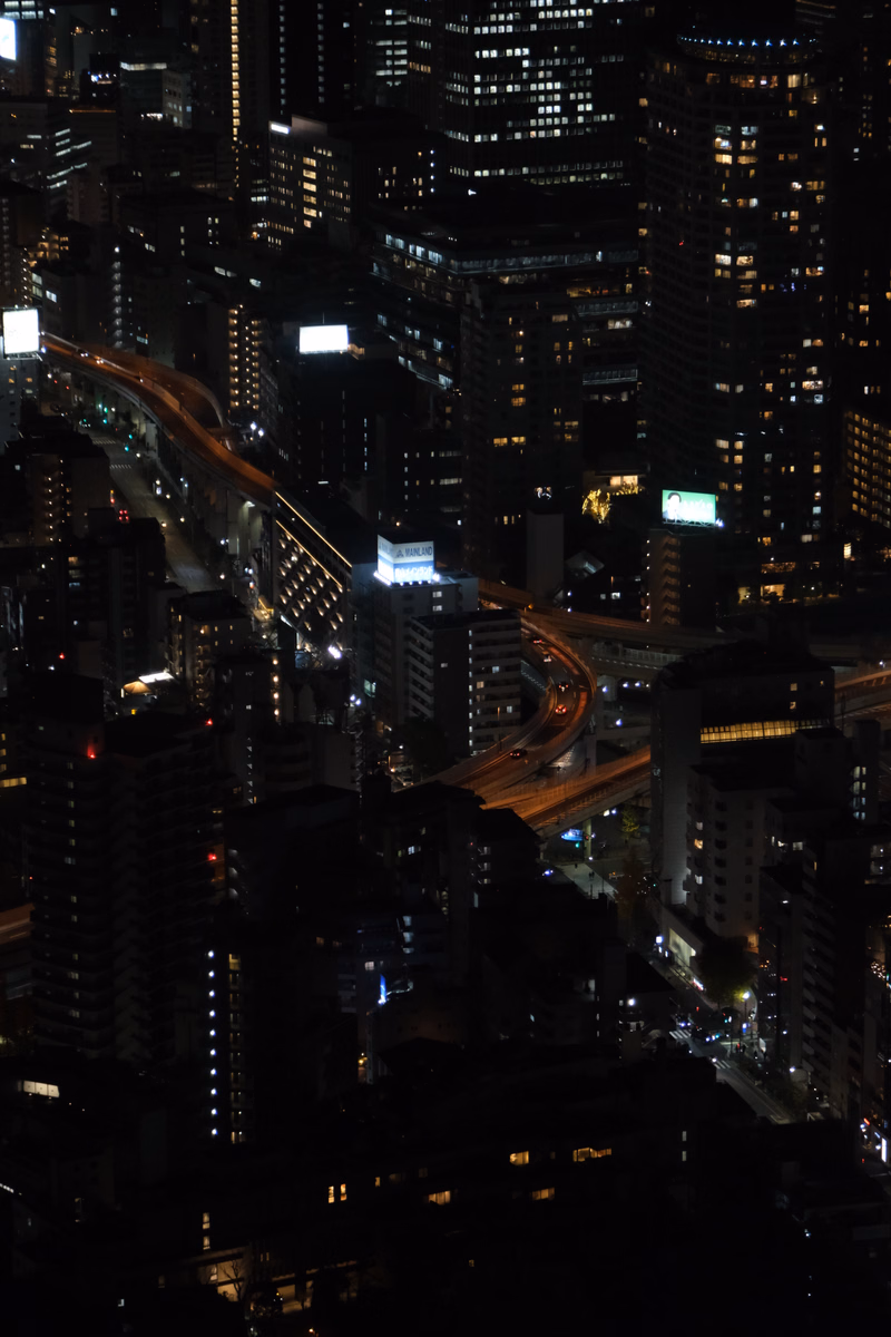 A nighttime cityscape view showing illuminated buildings and busy traffic flowing through city streets.